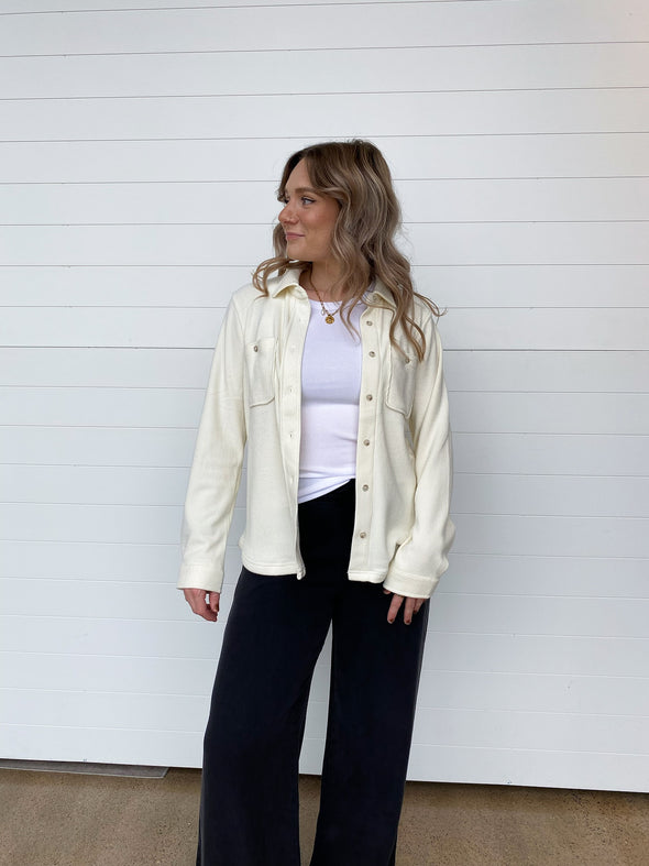 cream waffle knit jacket over a white shirt and black pants 